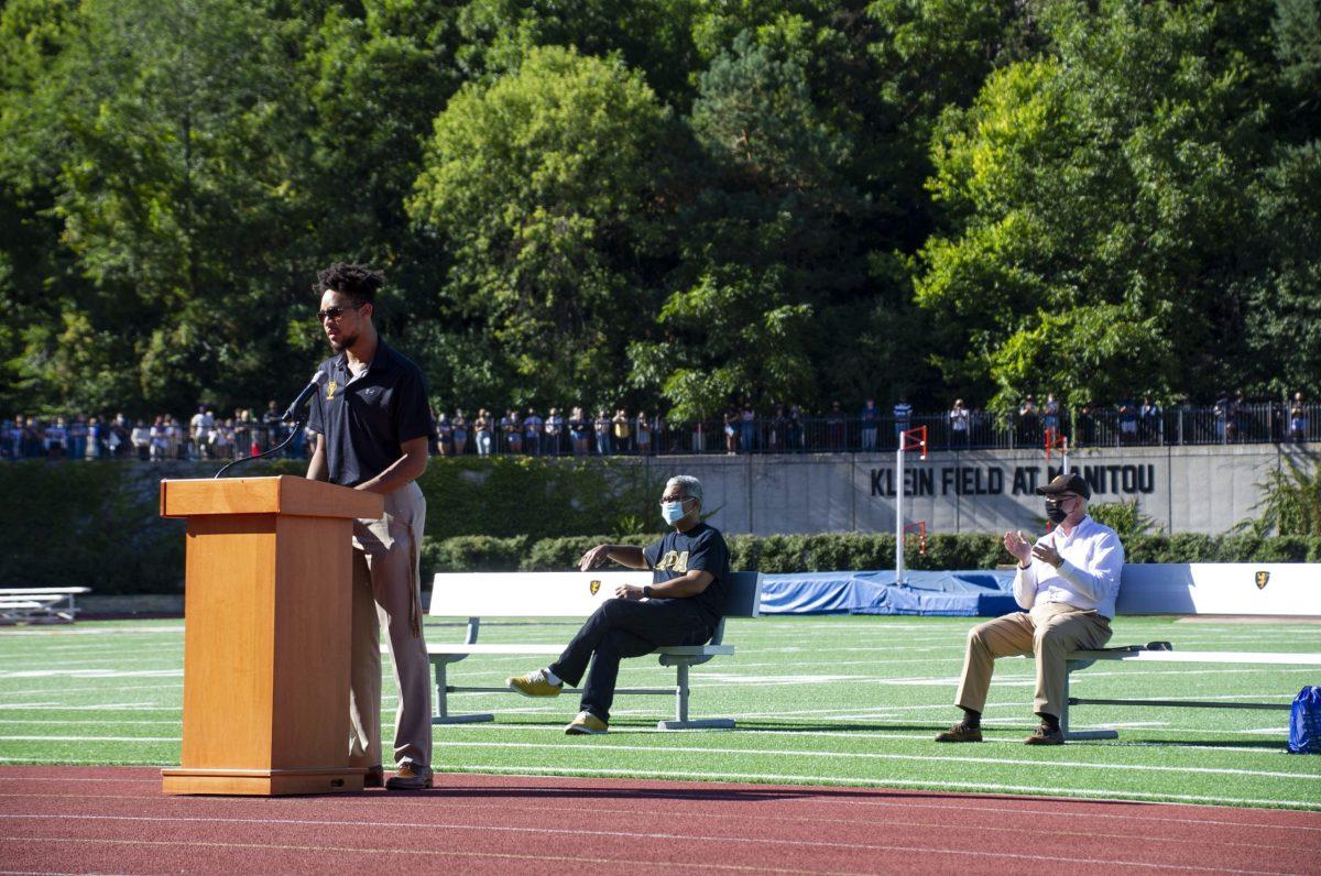 Aidan Lloyd '24 speaks at the "7 Feet for 7 Shots" march at Klein Field on Friday, Sept. 4. President David Anderson '74 and Vice President for Equity and Inclusion Bruce King seen sitting in background. Madelyn Wood/The Olaf Messenger