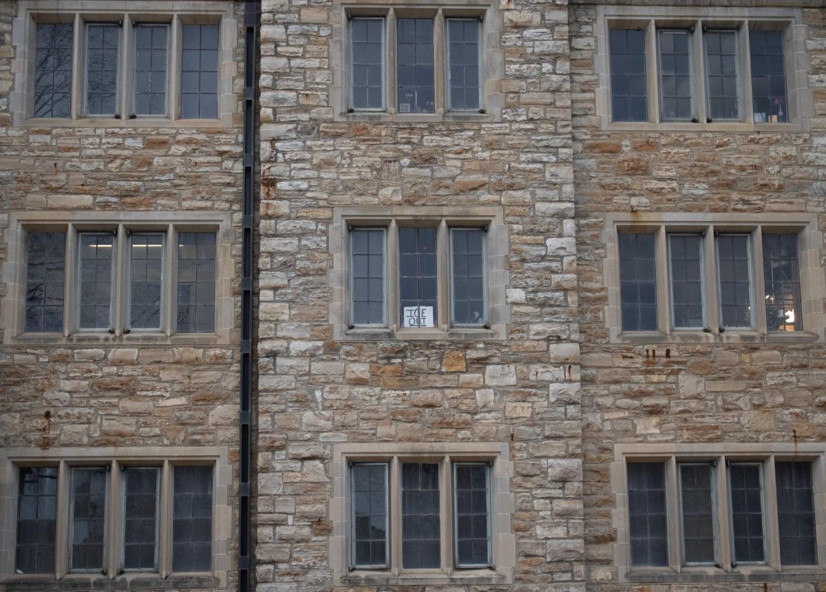 A sign reading "ICE OUT" is visible from a residential hall window. 